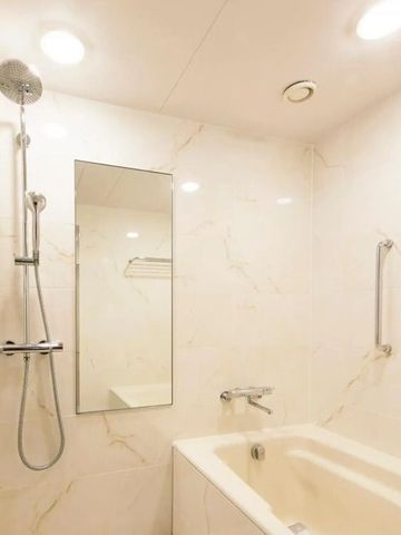 Helles Badezimmer mit Badewanne und Dusche in Marmoroptik