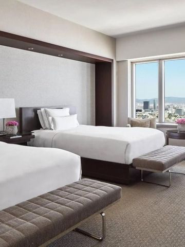 Modernes Hotelzimmer mit zwei Einzelbetten und Stadtblick durch großes Fenster