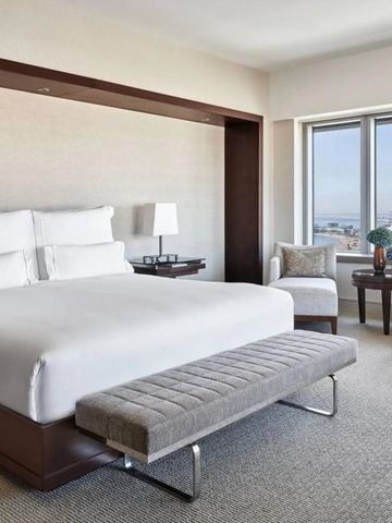 Hotelzimmer mit Doppelbett und Blick auf die Stadt durch großes Fenster