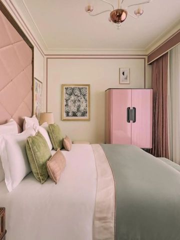 Luxuriöses Hotelzimmer mit rosa und grünen Akzenten und großen Fenstern.