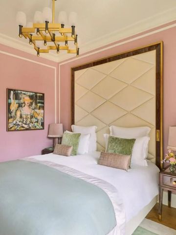 Elegantes Hotelzimmer mit pastellrosa Wänden und luxuriösem Bett