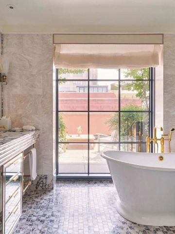 Geräumiges Badezimmer mit freistehender Badewanne und Marmordetails