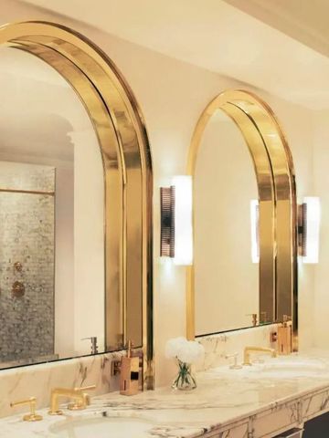 Luxuriöses Badezimmer mit goldenen Spiegelrahmen und Marmoroberflächen