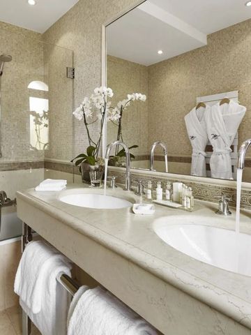 Modernes Badezimmer mit Doppelwaschbecken und luxuriösen Pflegeprodukten.