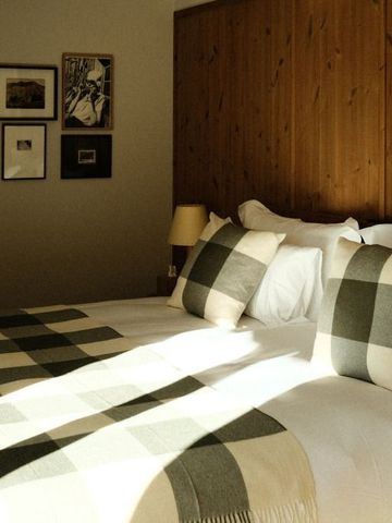 Luxuriöses Bett mit karierten Kissen in einem eleganten Hotelzimmer