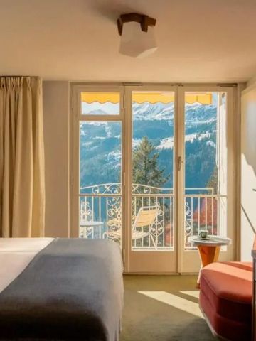 Geräumiges Hotelzimmer mit Balkon und Bergblick durch große Fenster.