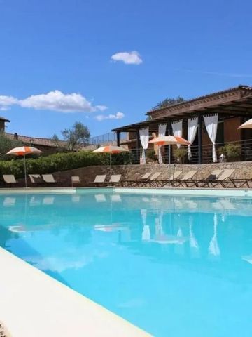 Hotel-Pool mit Liegestühlen und Sonnenschirmen im toskanischen Stil bei blauem Himmel
