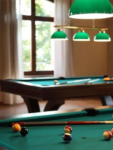 Billardraum mit Holztischen und grünen Hängelampen in elegantem Ambiente