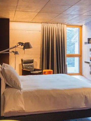 Modernes Hotelzimmer mit Doppelbett und großen Fenstern