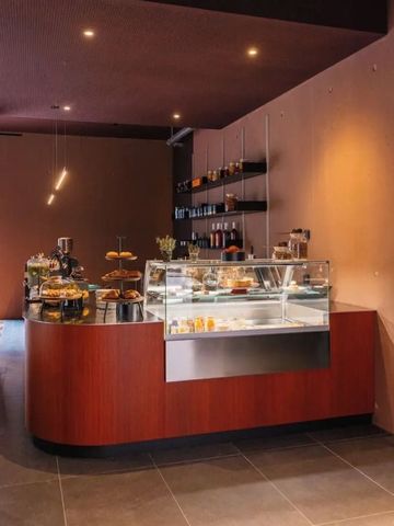 Elegantes Café mit Theke, Gebäck und modernen Holzoberflächen.