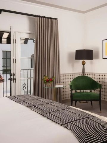 Elegantes Hotelzimmer mit Balkon, grünem Sessel und Kunst an der Wand