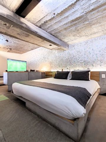 Hotelzimmer im industriellen Stil mit großem Bett und Fernseher