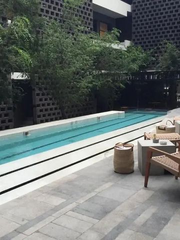 Langer, schmaler Pool in urbaner Umgebung mit gemütlichen Sitzmöglichkeiten