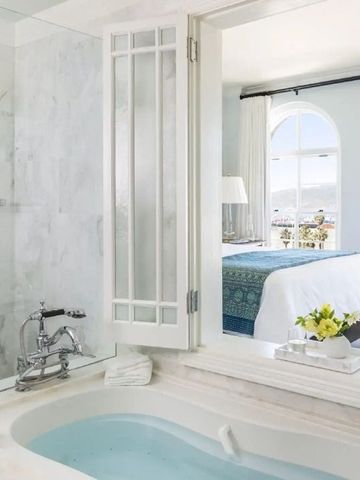 Luxuriöses Badezimmer mit Blick ins Schlafzimmer und blumigen Details