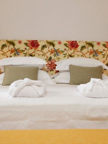 Doppelbett in warmen Farben mit floralem Kopfteil und weichen Kissen