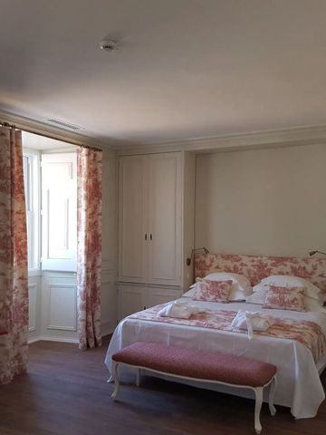 Helles Schlafzimmer mit Doppelbett und Fenster mit Blick auf die Umgebung im Hotel Casa Palmela