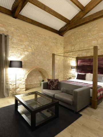 Elegantes Hotelzimmer mit freiliegenden Steinwänden und Holzbalken.