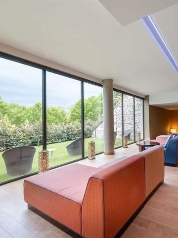 Lounge-Bereich mit großen Fenstern und Ausblick auf Garten.