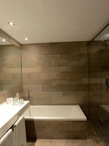 Modernes Badezimmer mit Badewanne und Glasdusche im Hotelzimmer.