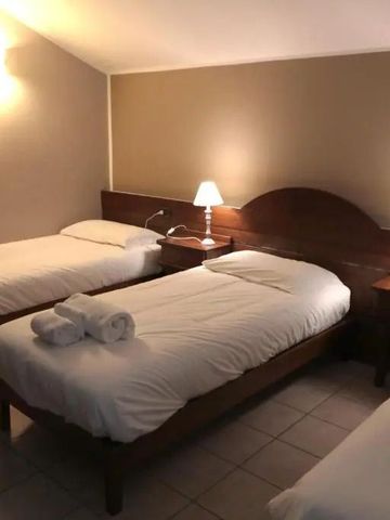 Ein Hotelzimmer mit drei Einzelbetten und gedämpfter Beleuchtung