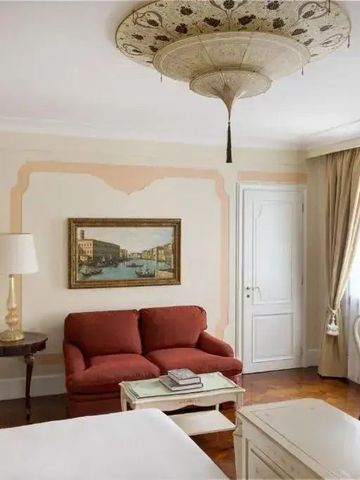 Elegantes Zimmer mit Kronleuchter und klassischem Dekor, rote Sofas, stilvolle Wandkunst