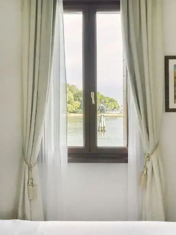 Helles Zimmer mit Blick auf das Wasser durch ein Fenster mit Vorhängen
