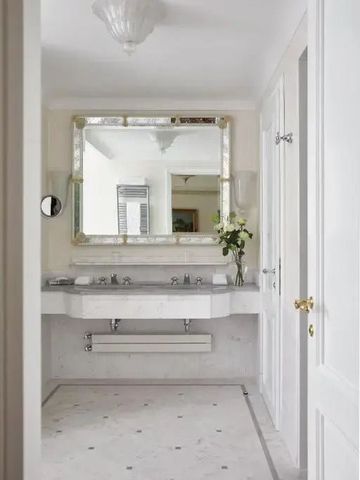 Stilvoll gestaltetes Badezimmer mit großem Wandspiegel und Blumenbouquet