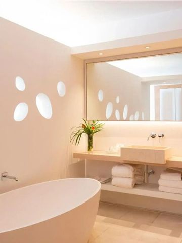 Luxuriöses Badezimmer mit freistehender Badewanne und großen Spiegeln.