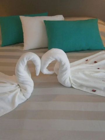 Doppelbett mit dekorativen Handtuchschwänen und türkisfarbenen Kissen