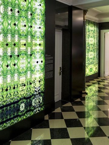 Kunstvoll gestalteter Hotelflur mit grünen Lichtelementen und Schachbrettmuster-Boden