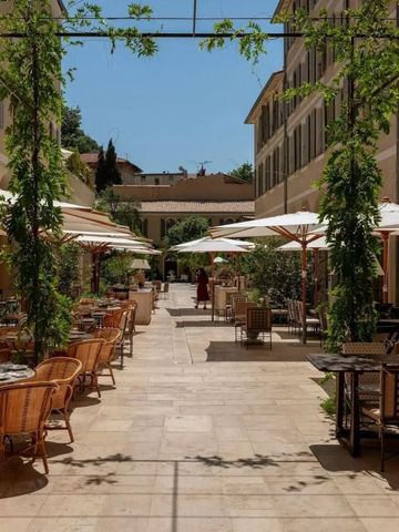 Sonnige Terrasse mit Tischen und Stühlen inmitten von Grünpflanzen