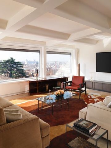 Helles Wohnzimmer einer Hotelsuite mit großzügigem Stadtblick durch große Fenster.