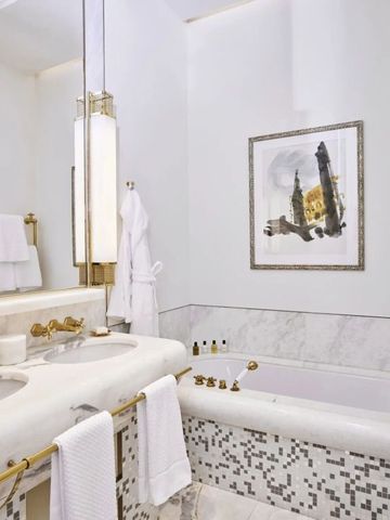 Luxuriöses Badezimmer mit Marmorverkleidung und goldenen Armaturen im Hotel.