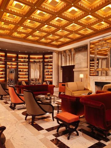 Luxuriöse Lounge mit goldener Decke und stilvollen Sesseln