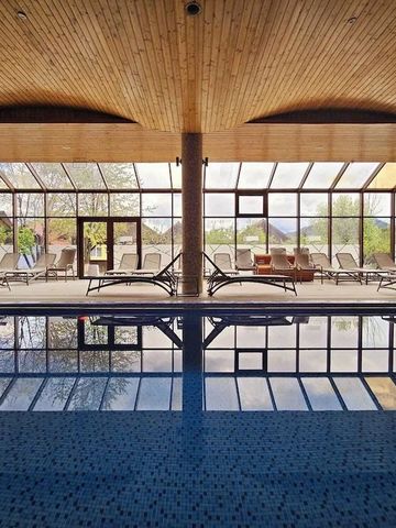 Indoor-Pool mit Panoramafenstern und Liegestühlen