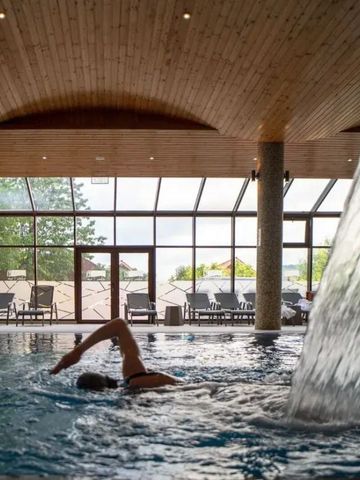Großes Indoor-Schwimmbecken mit Wasserfall und Schwimmer im Vordergrund