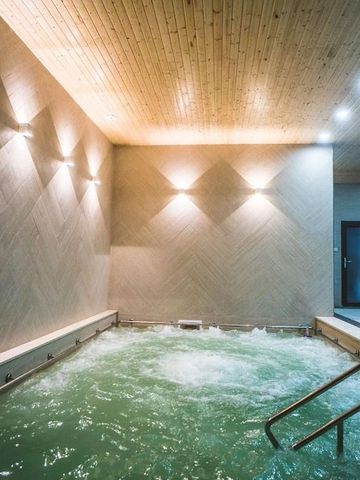 Wellnessbereich mit beleuchtetem Whirlpool und Holzdecke