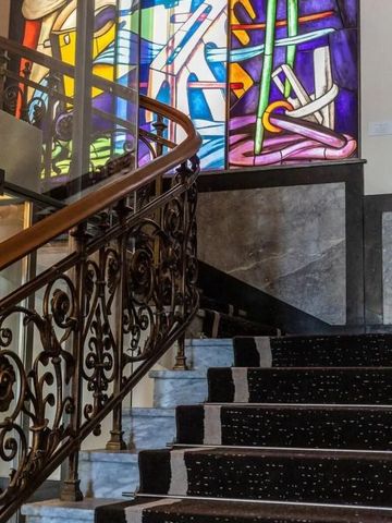 Buntes Glasfenster über geschwungener Treppe in Hotelinterieur