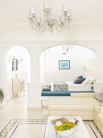 Elegantes Wohnzimmer mit cremefarbenem Sofa und kunstvoller Deckenlampe