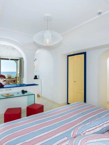 Zimmer mit gestreifter Bettwäsche und Meerblick durch ein offenes Fenster