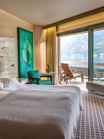Luxuriöses Hotelzimmer mit großem Bett und Blick auf einen See vom Balkon