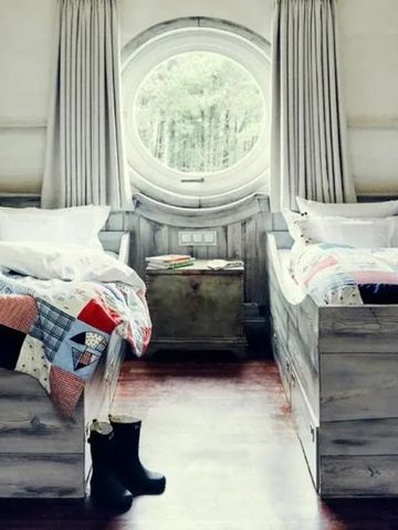 Stilvolles Zimmer mit zwei Betten, rundem Fenster und Holzboden