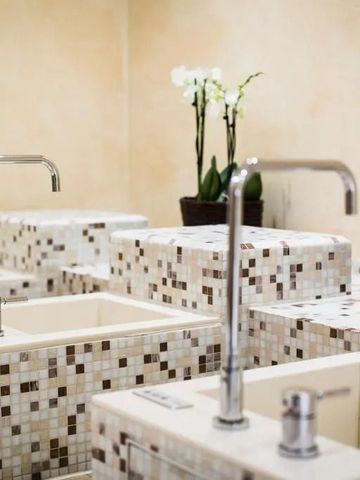 Waschbereich mit eleganter Keramikkachelung und Orchideen.