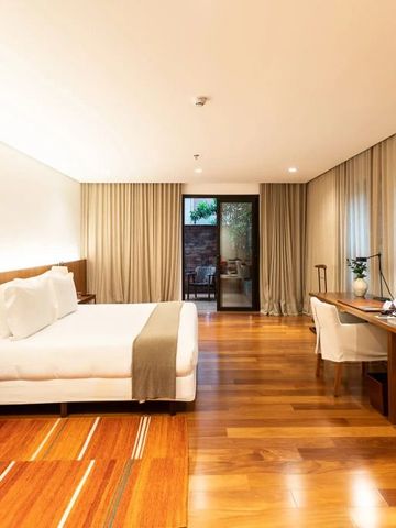 Modernes Hotelzimmer mit Holzboden, großem Bett und Schreibtisch, Blick zur Terrasse.