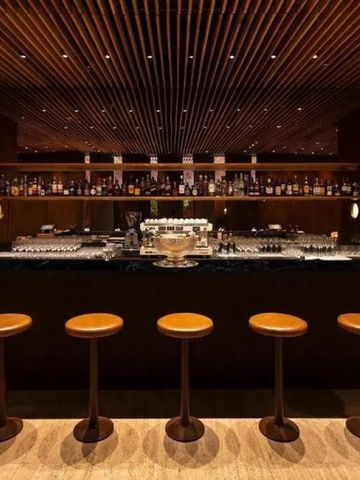 Elegante Hotelbar mit Holzdecke und beleuchtetem Bereich mit Sitzhockern