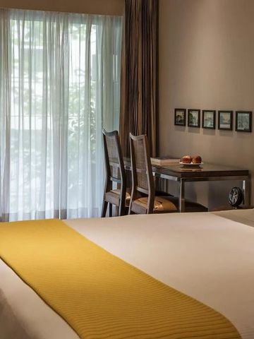 Gemütliches Zimmer mit großem Bett und Schreibtisch mit Stühlen. Fenster mit Vorhang.