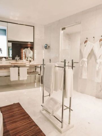 Helles Badezimmer mit Spiegel, Waschbecken und Bademänteln. Moderne Einrichtung.