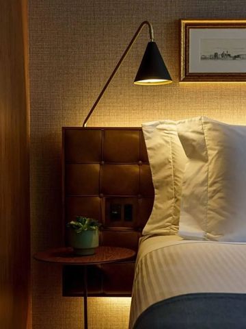 Nahaufnahme eines Bettes mit eleganter Beleuchtung und Kunstwerk an der Wand