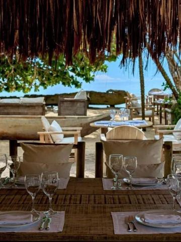 Strandrestaurant mit gedeckten Tischen und Meerblick