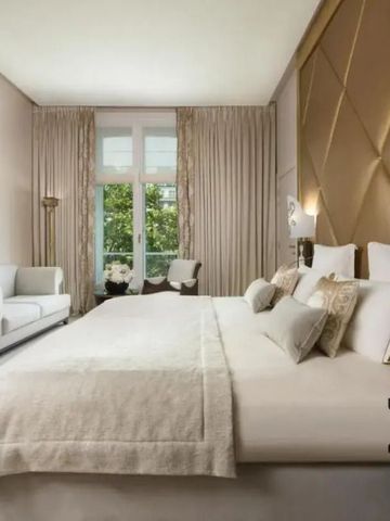 Elegantes Hotelzimmer mit Doppelbett, sitzbereich und großem Fenster mit Vorhängen